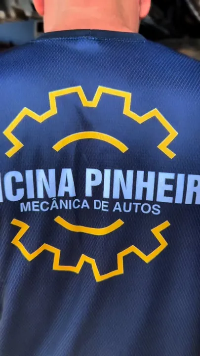 Costas da camisa azul-marinho da equipe com o logo de engrenagem da Oficina Pinheiro